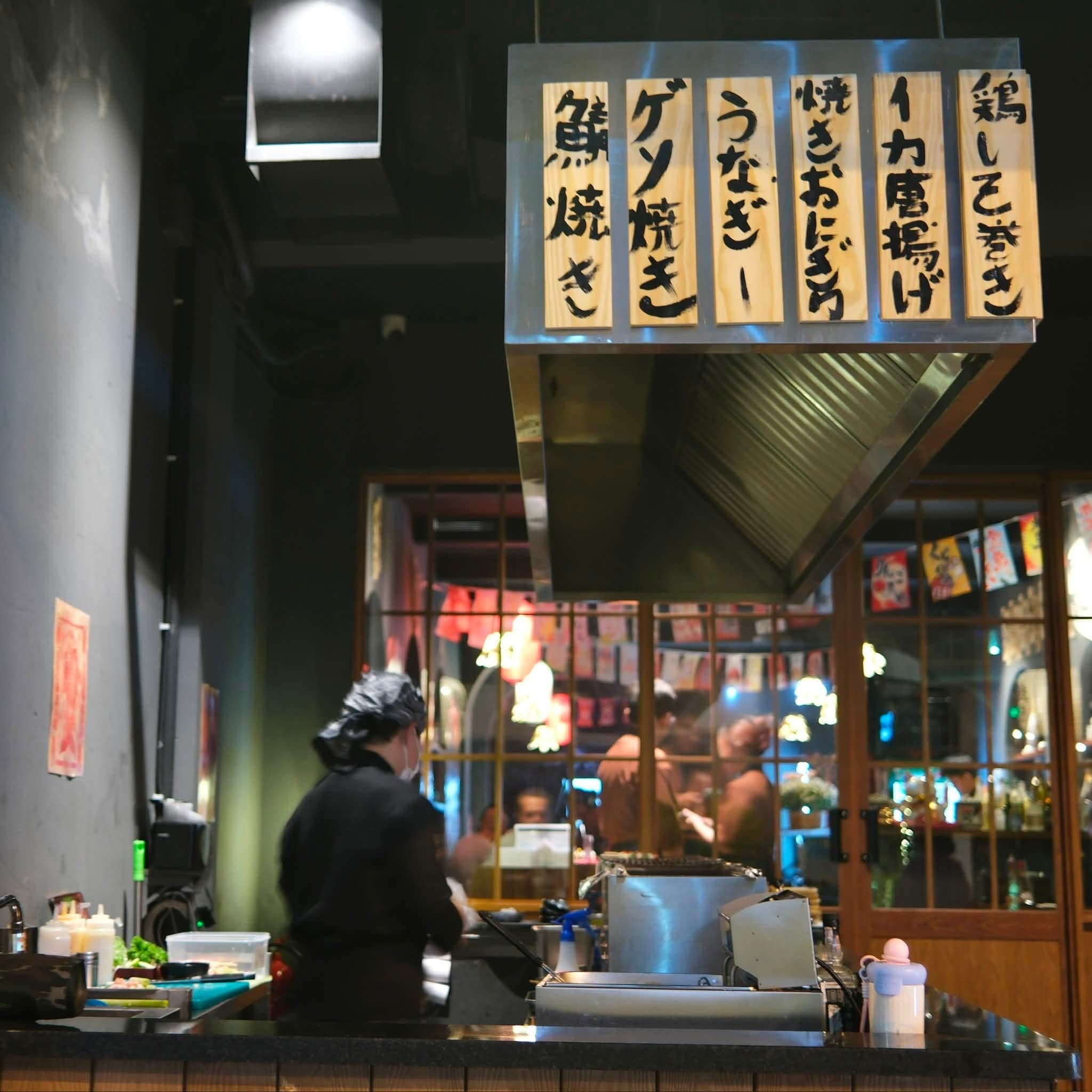 Tầng trệt EN Izakaya với quầy bar mở và ánh đèn vàng ấm